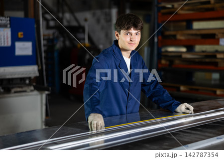 Positive young worker marking steel sheet in metal workshop Positive young worker marking steel sheet in metal workshop 142787354