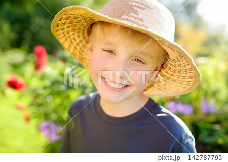 Portrait of preteen boy wearing stray hat on the domestic garden at summer sunny day. Summertime holidays for kids in the village Portrait of preteen boy wearing stray hat on the domestic garden at summer sunny day. Summertime holidays for kids in the village 142787793