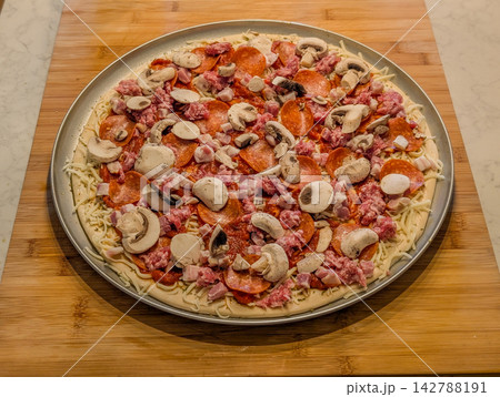 Unbaked pizza with pepperoni mushrooms sausage and cheese Unbaked pizza with pepperoni mushrooms sausage and cheese 142788191
