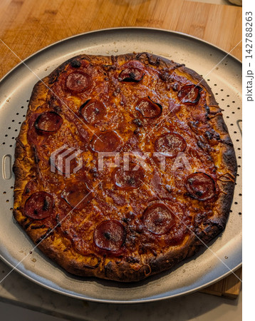 Baked pepperoni pizza with dark charred crust Baked pepperoni pizza with dark charred crust 142788263