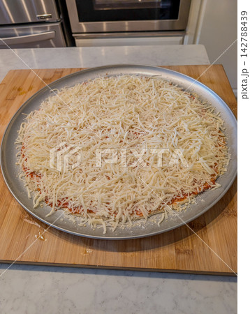 Unbaked plain cheese pizza on metal baking pan 142788439