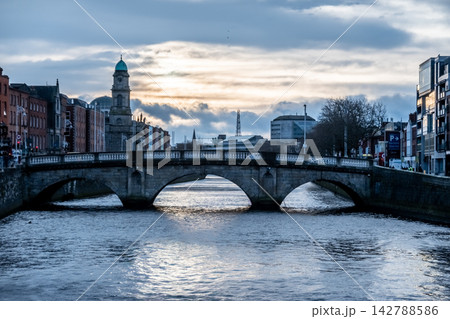Dublin Ireland Cityscape Along River Liffey with Historic Bridges Waterfront Buildings and Overcast Winter Sky Atmosphere Dublin Ireland Cityscape Along River Liffey with Historic Bridges Waterfront Buildings and Overcast Winter Sky Atmosphere 142788586