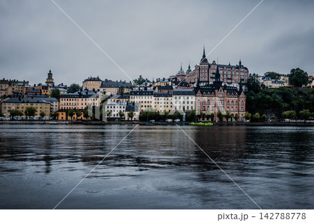 Stockholm Sweden Sodermalm Waterfront with Historic Munchenbryggeriet Building and Boat on Calm Water Under Overcast Sky Stockholm Sweden Sodermalm Waterfront with Historic Munchenbryggeriet Building and Boat on Calm Water Under Overcast Sky 142788778