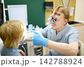 An experienced male ENT doctor examines a young patient's nose in a medical office. A professional otolaryngologist is at his workplace 142788924