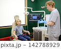 An experienced otolaryngologist prepares to examine a preteen boy patient in the medical office. The doctor puts on sterile medical gloves. The professional ENT specialist is at their workplace. 142788929