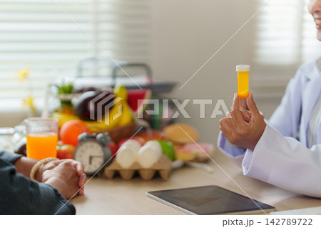 Nutritionist holding pill bottle during patient consultation for healthy diet guidance Nutritionist holding pill bottle during patient consultation for healthy diet guidance 142789722