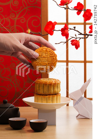 Cropped hand holding mooncake for Mid-Autumn Festival celebration Cropped hand holding mooncake for Mid-Autumn Festival celebration 142789742