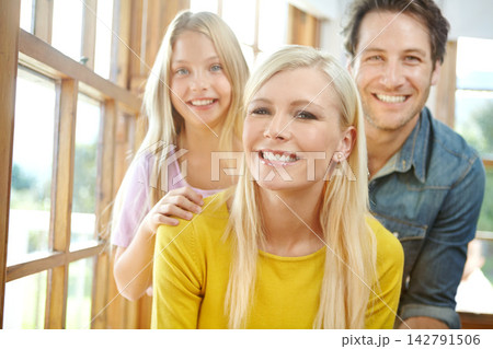 Happy family, portrait and relax with window for bonding, holiday or weekend together at home. Mother, father and young daughter with smile or hug for love, care or embrace in living room at house Happy family, portrait and relax with window for bonding, holiday or weekend together at home. Mother, father and young daughter with smile or hug for love, care or embrace in living room at house 142791506