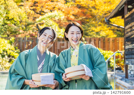 紅葉が映える露天風呂で湯桶を持ち笑顔を見せるミドル世代の女性 紅葉が映える露天風呂で湯桶を持ち笑顔を見せるミドル世代の女性 142791600