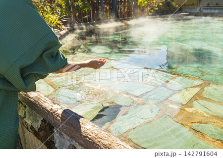 露天風呂のお湯にそっと手を触れる女性の手元 露天風呂のお湯にそっと手を触れる女性の手元 142791604