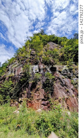 青空と断崖絶壁に広がる緑豊かな山の風景 142792277
