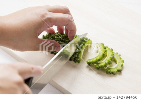 綿を取ったゴーヤを包丁で薄切りにする手元 綿を取ったゴーヤを包丁で薄切りにする手元 142794450