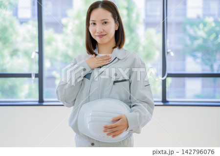 胸に手を当てる作業着の若い女性 ポートレート 胸に手を当てる作業着の若い女性 ポートレート 142796076