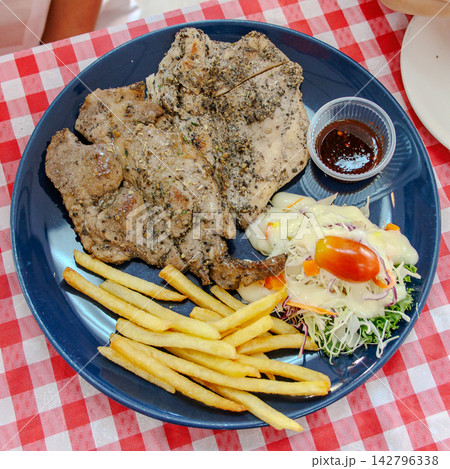 Pork steak served with vegetables, French fries Pork steak served with vegetables, French fries 142796338