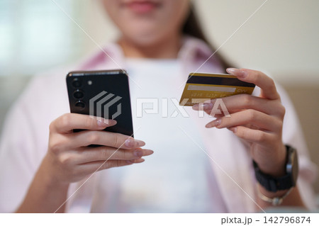 Cropped view of woman holding smartphone and credit card for online mobile shopping payment Cropped view of woman holding smartphone and credit card for online mobile shopping payment 142796874