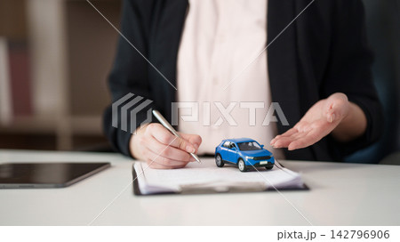 Car insurance agent explaining policy terms with vehicle model on desk for auto coverage 142796906