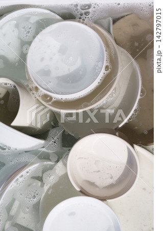 Ceramic plates and bowls soaking in soapy water with bubbles. 142797015