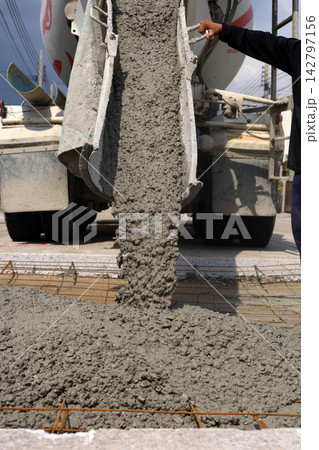 Wet cement pouring from a mixer truck chute onto a steel wire mesh for road Wet cement pouring from a mixer truck chute onto a steel wire mesh for road 142797156