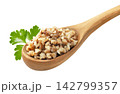 Boiled buckwheat in a wooden spoon with a parsley leaf, close-up on a white background. Isolated 142799357