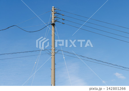 青空を背景に立つコンクリート製の電柱と電線 142801266