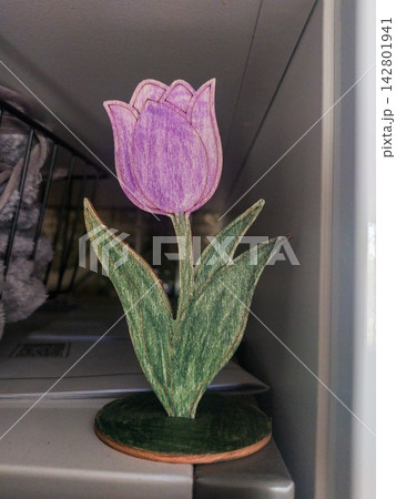 This charming handmade wooden tulip decoration stands elegantly on a shelf, evoking a warm, cozy, and rustic spring feeling. Ideal for creative home decor concepts. Nobody is present. 142801941