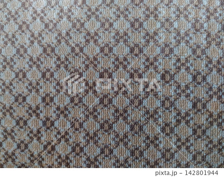 This closeup of a warm, cozy woven fabric texture features an intricate brown and beige geometric pattern, offering a comforting and rustic backdrop for interior design nobody. 142801944