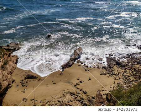 A serene highangle view of powerful ocean waves crashing onto a rocky sandy beach, evoking feelings of freedom, energy, and peaceful solitude. Great for travel concepts. Nobody. 142801973