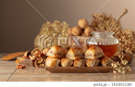 Baklava with walnuts and honey on a beige background. Baklava with walnuts and honey on a beige background. 142802186