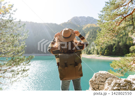 Young woman traveler enjoys fresh air and a beautiful view of the lake and mountains. Active life Young woman traveler enjoys fresh air and a beautiful view of the lake and mountains. Active life 142802550