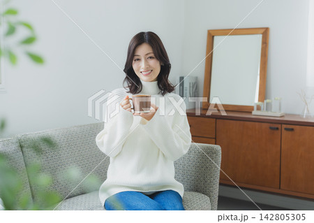 リビングでコーヒーを飲むミドル女性 リビングでコーヒーを飲むミドル女性 142805305