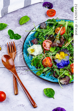 Arugula and Tomato Salad with Edible Flowers on Gray Background Arugula and Tomato Salad with Edible Flowers on Gray Background 142805452