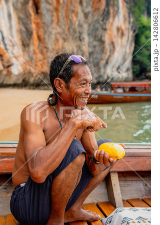 Smiling thai man eating mango on longtail boat Smiling thai man eating mango on longtail boat 142806612
