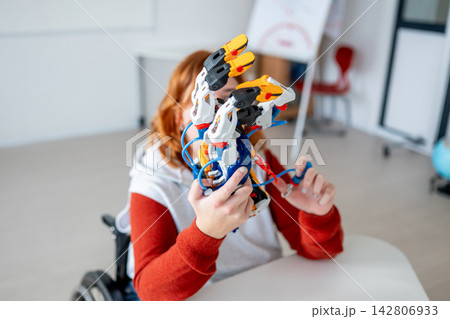 Female student in wheelchair presenting robotic project in front of classroom. Female student in wheelchair presenting robotic project in front of classroom. 142806933