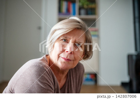Smiling elderly woman looking through window at home. 142807006