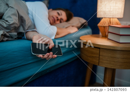 Tired middle aged woman sleeping in bed after using smartphone. Tired middle aged woman sleeping in bed after using smartphone. 142807093