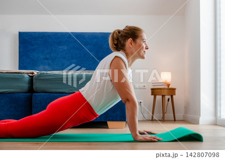 Woman practicing yoga in bedroom at home. 142807098