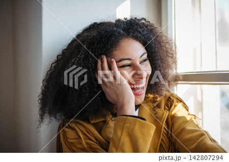 Portrait of beautiful young woman sitting on window sill. Portrait of beautiful young woman sitting on window sill. 142807294
