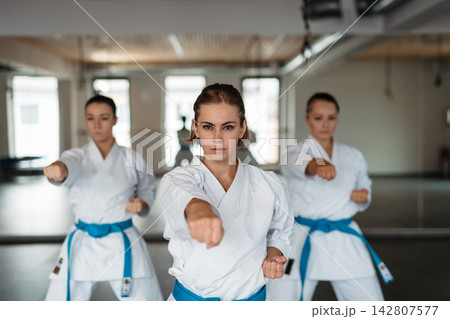 Focused female karate fighters practicing punch technique. Focused female karate fighters practicing punch technique. 142807577