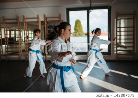 Women practicing karate kata in martial arts studio. Women practicing karate kata in martial arts studio. 142807579