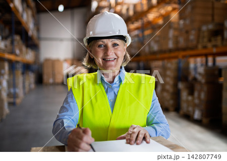 Senior woman manager or supervisor standing in a warehouse, arms crossed. Senior woman manager or supervisor standing in a warehouse, arms crossed. 142807749