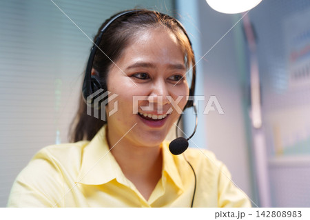 Smiling Customer Service Assistant Wearing Headset at Call Center Smiling Customer Service Assistant Wearing Headset at Call Center 142808983