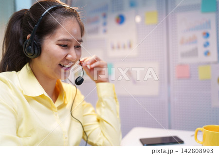 Smiling Call Center Assistant Wearing Headset in Modern Office 142808993