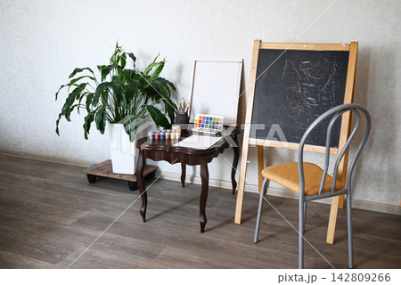 Creative workspace features painting supplies, brushes, and colorful materials ready for an art project at a desk Creative workspace features painting supplies, brushes, and colorful materials ready for an art project at a desk 142809266