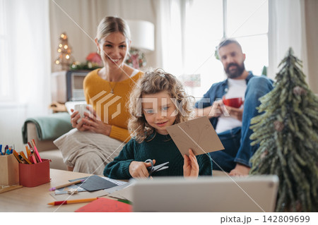 Little girl writing Christmas wish list for Santa with parents at home. Little girl writing Christmas wish list for Santa with parents at home. 142809699