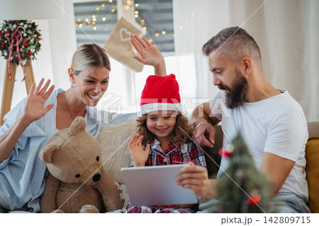 Family making Christmas video call with relatives during holiday celebration at home. Family making Christmas video call with relatives during holiday celebration at home. 142809715