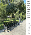 Wooden park bench, surrounded by grass and trees in a city park. 142810515