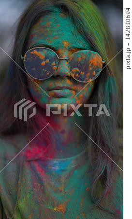 Portrait of girl standing being covered in coloured powder at holi festival Portrait of girl standing being covered in coloured powder at holi festival 142810694