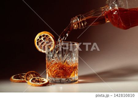 Whiskey is poured into a in crystal glass garnished with dried orange slices. Whiskey is poured into a in crystal glass garnished with dried orange slices. 142810810