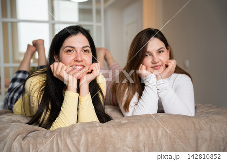 Two adult women relaxing together on a sofa in a cozy home interior. Female friendship home comfort and sleepover lifestyle Two adult women relaxing together on a sofa in a cozy home interior. Female friendship home comfort and sleepover lifestyle 142810852