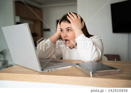 Frustrated woman reacting to unexpected online information on laptop at home office desk. Digital stress remote work and technology support Frustrated woman reacting to unexpected online information on laptop at home office desk. Digital stress remote work and technology support 142810856